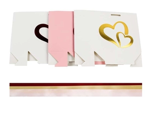 Flat lay of white and pink gift bags with gold foil double heart and satin ribbons
