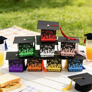 Detalle de cajas de regalo con forma de birrete y borlas de seda en mesa de picnic