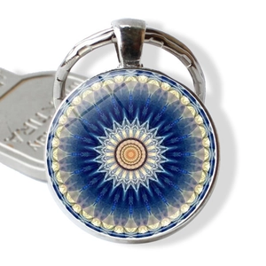 Macro detail of silver mandala keychain with blue geometric pattern and glass dome cover