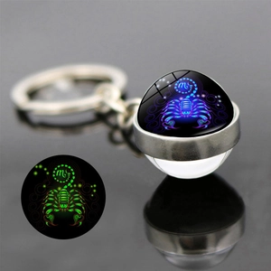 Luminous Scorpio glass ball keychain showing green glow effect in dark with metal ring