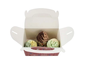 Close-up of white paper gift box with three slots holding cupcakes and Valentine text