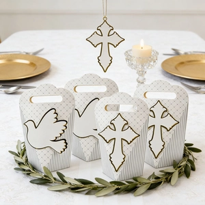 Dettaglio di scatole regalo per battesimo bianche con croce dorata e colomba sulla tavola