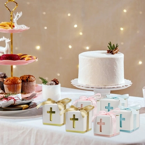 Detailed view of hollow cross favor boxes with gold, pink, and blue ribbons on table