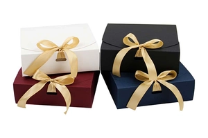 Detailansicht quadratischer matter Geschenkschachteln in mehreren Farben mit goldener Schleife
