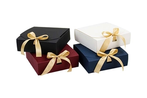 Quadratische Geschenkschachteln in Schwarz, Rot, Weiß und Blau mit goldenen Schleifen
