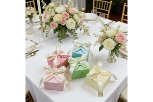 Detail of macaron-colored wedding gift boxes with cream bow ribbons on a banquet table