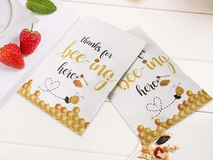 Detail view of bee themed paper gift bags with thanks for bee-ing here typography