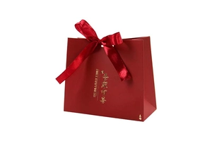 Detail of red wedding favor bag with golden Sweet Happiness text and a satin ribbon bow