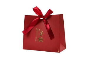 Detail showing red wedding favor box with gold foil lettering and satin ribbon bow