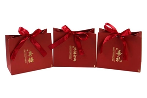 Detail of red wedding favor bags with gold foil lettering and red satin bows