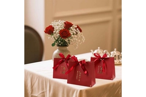 Three red Chinese wedding candy boxes with gold text and decorative ribbon bows
