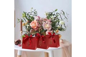 Detailed view of red wedding gift bags with golden calligraphy and silk ribbon bows