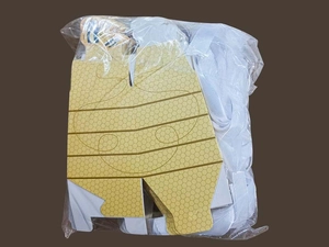 Flat pack of yellow honeycomb favor boxes with white ribbons in clear packaging