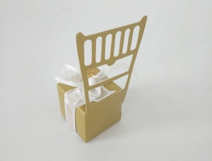 Close-up of golden laser-cut chair-shaped candy gift box with elegant white organza ribbon