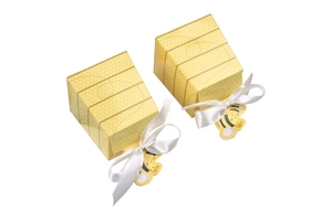 Detail of bee themed favor box with honeycomb pattern, white ribbon and bee tag
