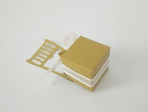 Detail of a gold wedding favor box with white ribbon and ornate laser cut chair design