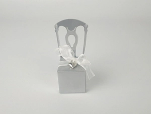 Detail of silver chair gift box featuring hollow backrest and white ribbon with heart pendant
