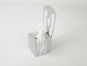 Close-up of silver chair-shaped candy box with white organza ribbon and heart charm
