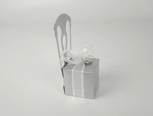 Silver chair-shaped gift box with intricate hollow pattern and white ribbon detail