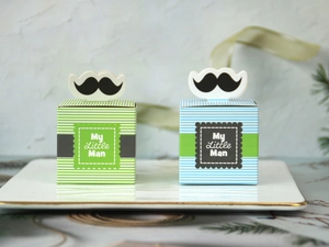 Close-up of blue and green striped candy boxes with black mustache detail on a tray