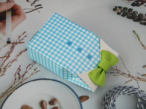 Detail of shirt-shaped candy box with blue plaid pattern and green grosgrain bow tie