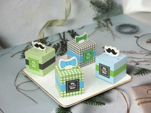 Detailed view of My Little Man candy boxes with bow ties and mustache toppers on a tray