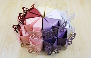 Top view of laser-cut butterfly candy boxes arranged in a circle on a wooden background