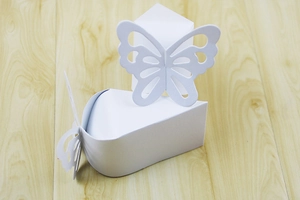 Close-up of a laser-cut white paper candy box featuring a delicate butterfly cutout design