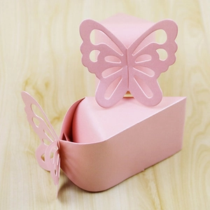 Pink pearl paper candy boxes with 3D butterfly cutouts on a light wooden background