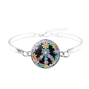 Macro view of silver-tone peace symbol bracelet with floral glass cabochon charm detail