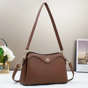 Close-up of brown textured leather crossbody bag with striped embossing and gold logo