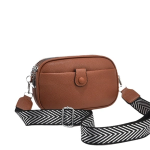 Brown lychee leather crossbody bag with dual zippers and geometric canvas strap