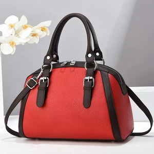 Detailed close-up of two-tone red and brown pebbled leather handbag with metal buckle