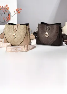 Detail view of monogram bucket bags in beige and brown with adjustable wide straps