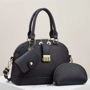 Black pebbled leather tote bag set with golden hardware and matching pouches on white stand