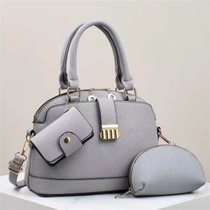 Three-piece grey-purple pebble leather tote bag set with gold hardware on marble base