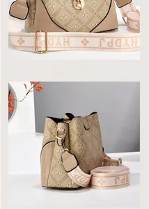 Detailed close-up of beige bucket bag featuring patterned monogram and wide webbing strap