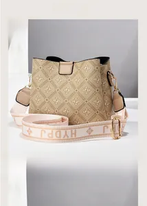Close-up of stylish bucket bag featuring monogram print and golden metal shoulder strap hardware