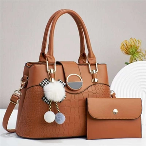 Detail of brown leather tote bag with crocodile pattern and decorative plush charm