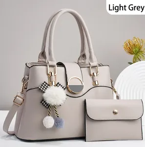 Détail d'un ensemble sac à main gris clair avec finitions dorées et nœud en peluche