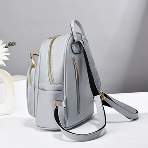 Detalle de las cremalleras doradas y el bolsillo antirrobo en la mochila gris para mujer