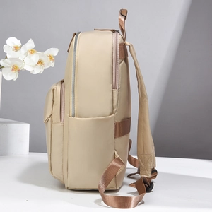 Side view of beige nylon backpack showing multi-layer zippers and adjustable straps