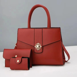 Close-up of red leather handbag set with gold floral buckle and black edge detail