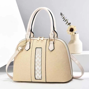 Minimalist beige shell dome bag with white leather trim and gold metal hardware