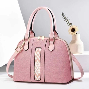 Pink shell tote bag with geometric webbing and gold hardware on white steps