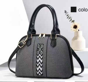 Detail of grey textured fabric handbag with black leather trim and geometric pattern