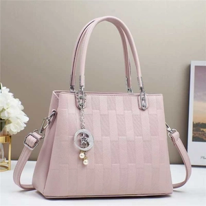 Detail of pink macaron handbag with woven texture, star-moon pendant and strap