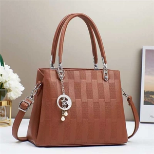 Macro view of brown braided leather handbag with silver star and pearl charms