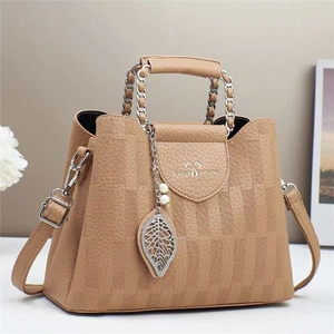 Detail of khaki bucket bag with plaid pattern, metal leaf charm and pearl accessory