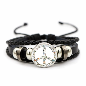 Detail of woven leather bracelet featuring a butterfly peace sign glass dome charm